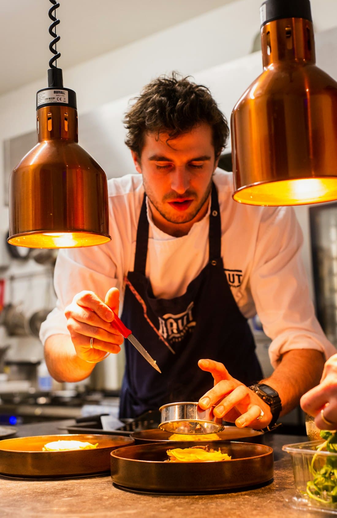 Chef plating dishes under copper pendant lights